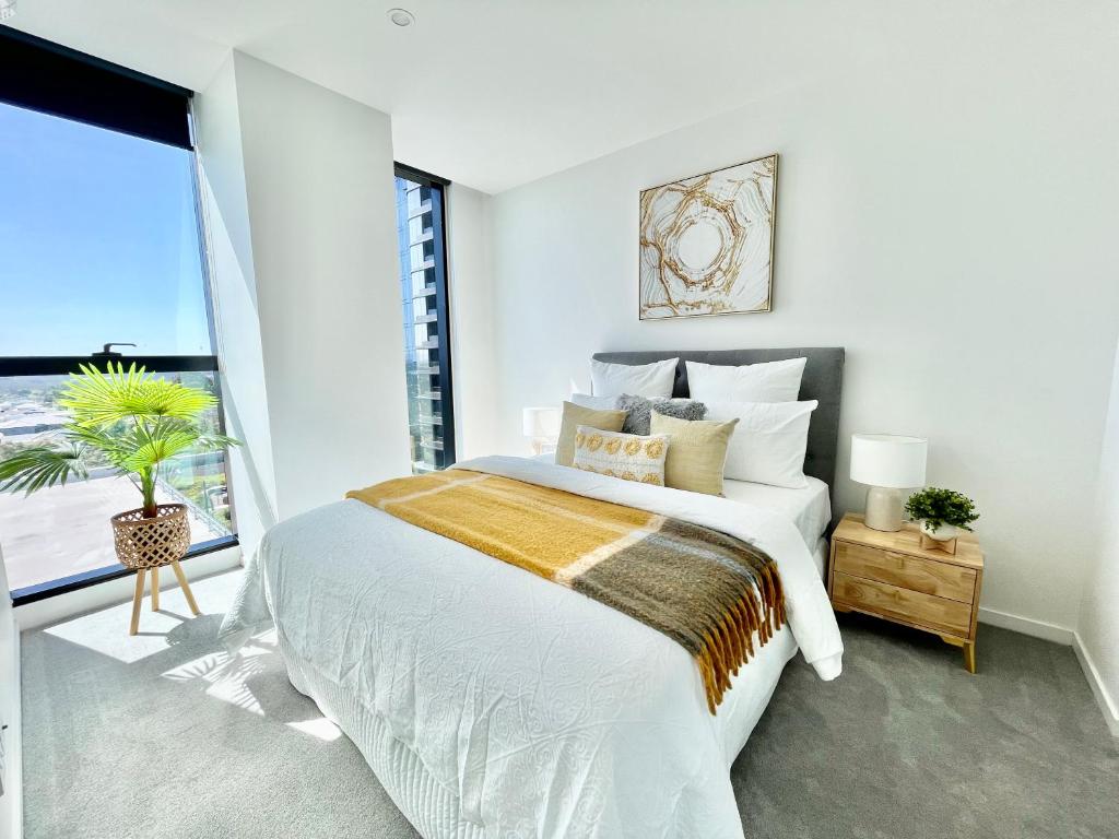 a white bedroom with a large bed and a window at Rest Skygarden Collection in Glen Waverley