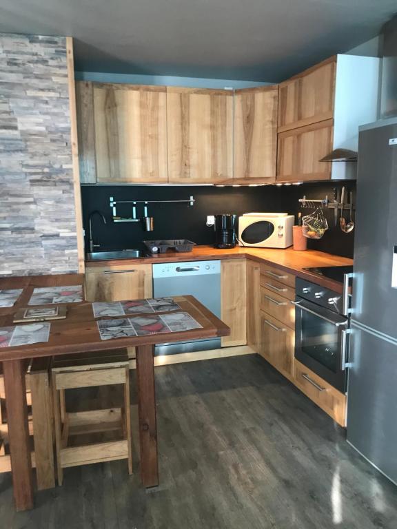 a kitchen with wooden cabinets and a table and a refrigerator at Les Marmottes 2 in Orcières