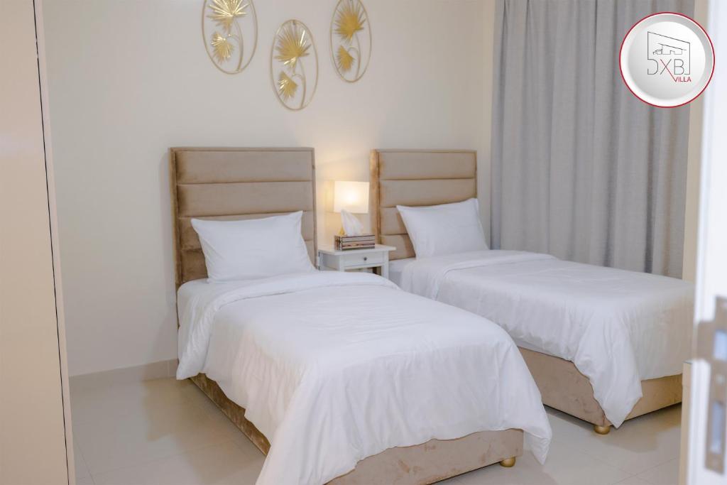 a bedroom with two beds with white sheets at 5 bedroom Villa - Dubai Hills in Dubai