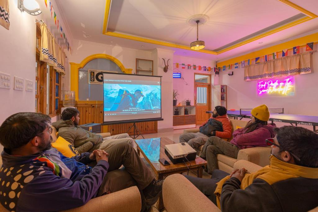 a group of people sitting in a room playing a video game at The Hosteller Narkanda in Nārkanda