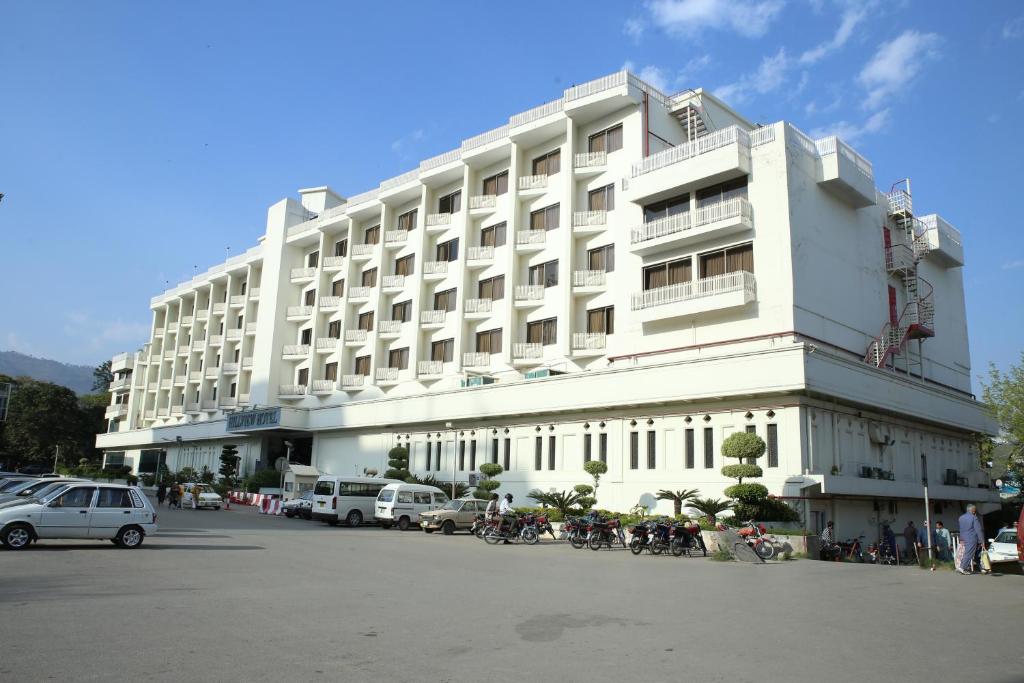 un gran edificio blanco con coches estacionados frente a él en Hotel Hillview Islamabad en Islamabad