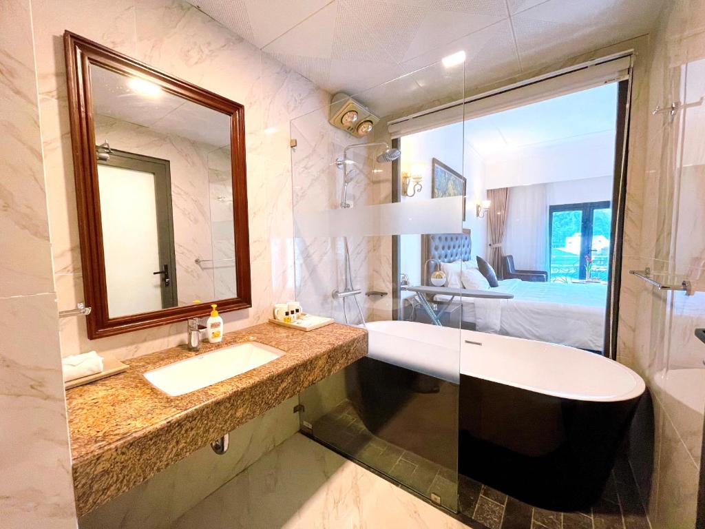 a bathroom with a sink and a mirror and a bed at Phoenix Hotel Hà Giang in Ha Giang