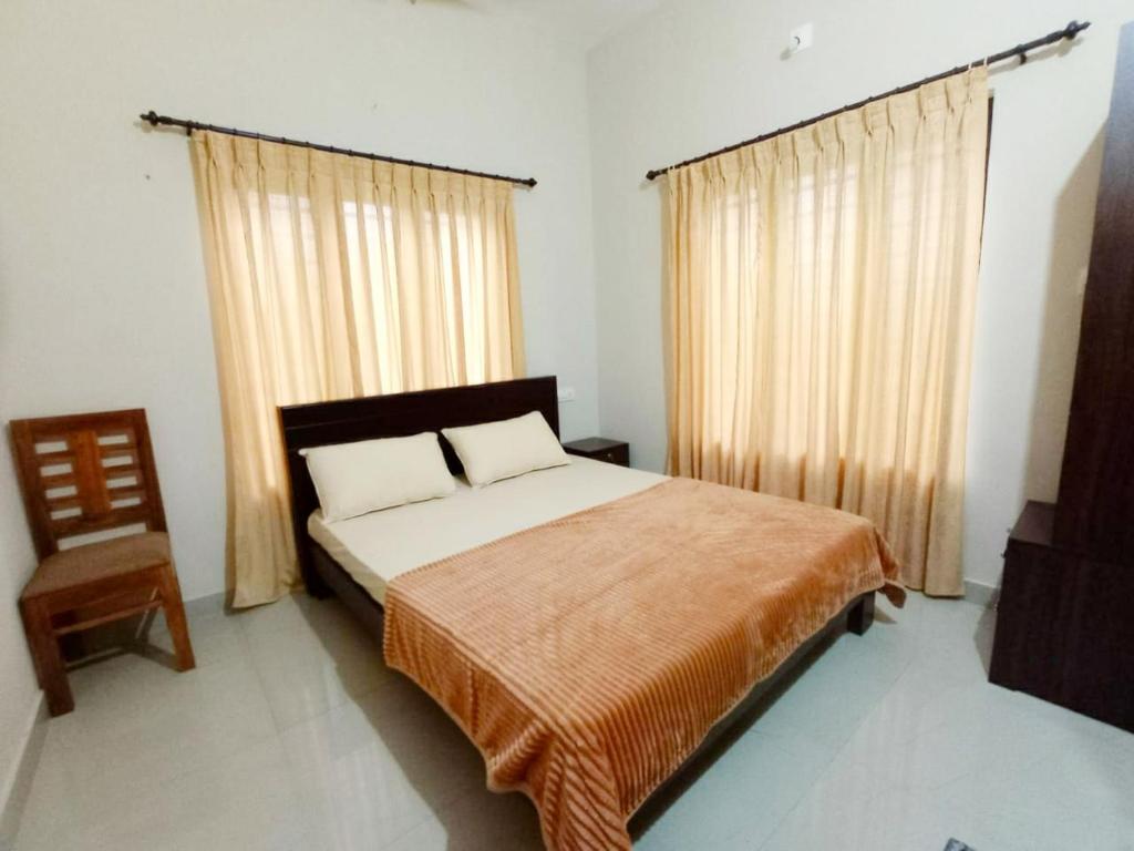 ein Schlafzimmer mit einem großen Bett und einem Stuhl in der Unterkunft Eve's Residency in Meppādi