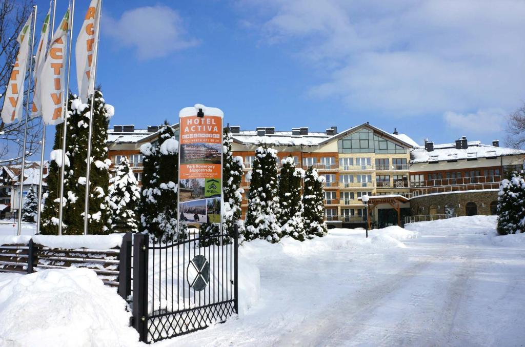 a snow covered street with a gate and buildings at Hotel Activa in Muszyna
