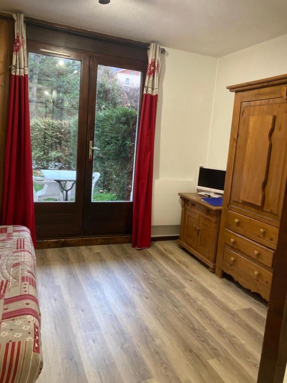 a room with a bed and a window with red curtains at studio Les Glieres in Bourg-Saint-Maurice