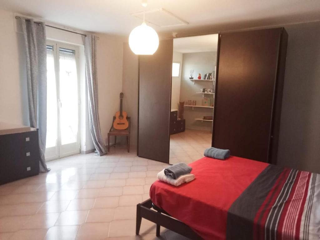 a bedroom with a red bed and a room with a guitar at bed and breakfast- Ai piedi del parco in San Donato Val di Comino