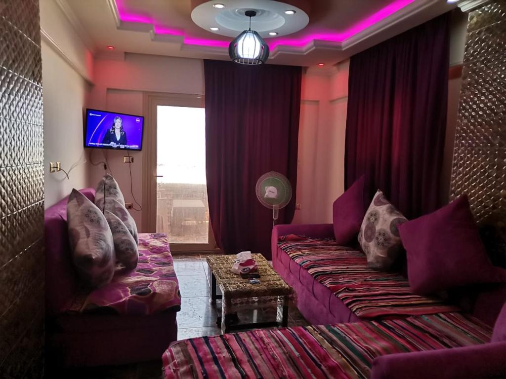 salon z fioletową kanapą i telewizorem w obiekcie Family Condo With Panoramic Sea View 1 w Aleksandrii