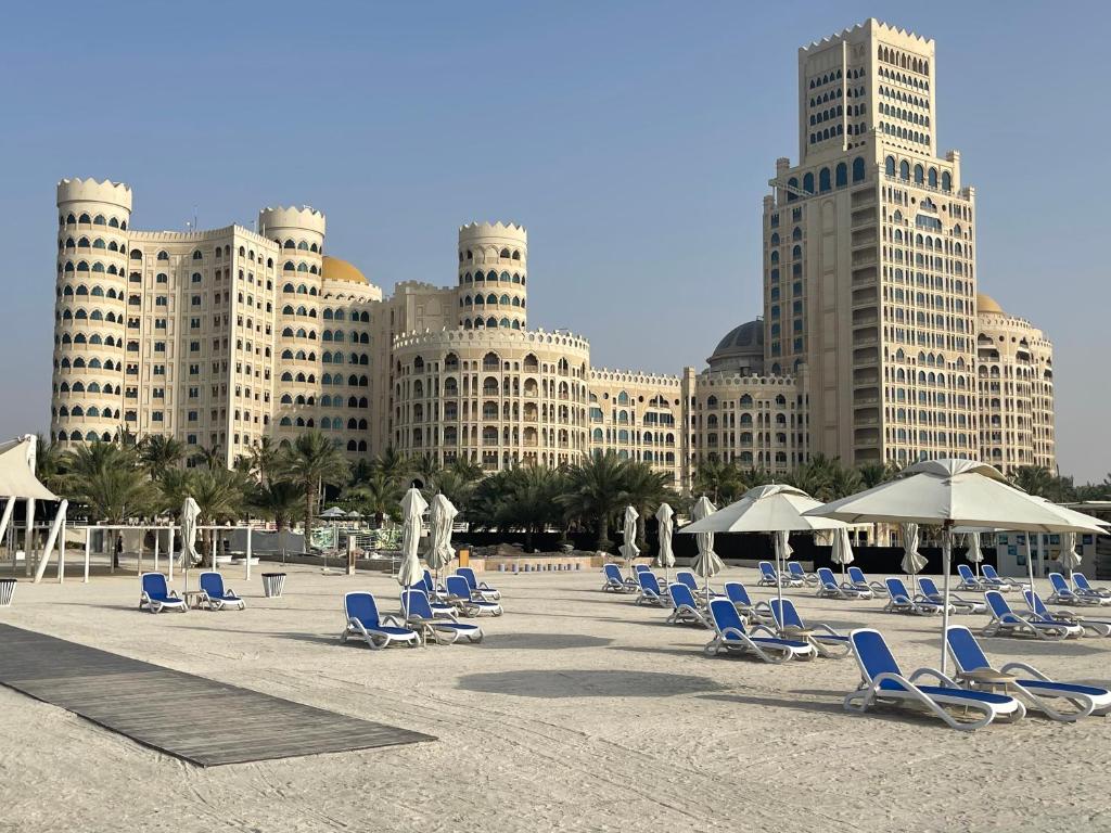 plaży z leżakami, parasolami i budynkami w obiekcie Private Suites Al Hamra Palace at golf & sea resort w mieście Ras al-Chajma