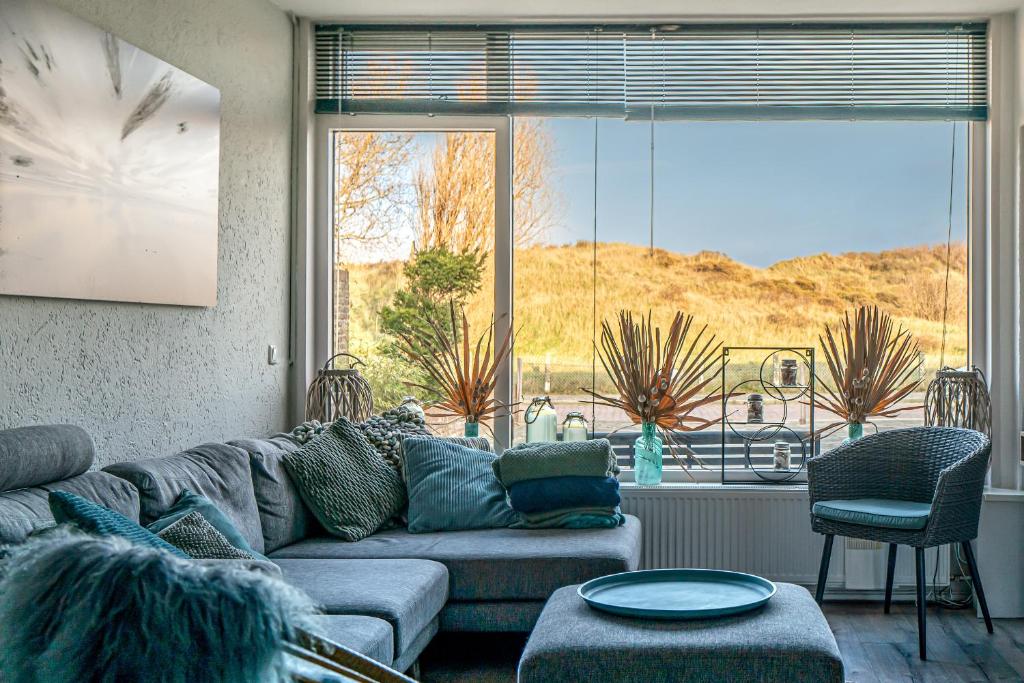 a living room with a couch and a large window at Alibi aan Zee in Wijk aan Zee