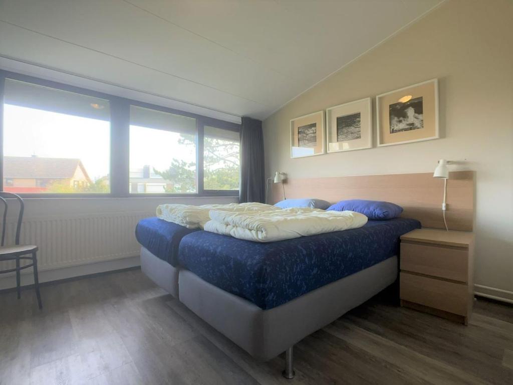 een slaapkamer met een bed met blauwe lakens en 2 kussens bij Wijk de Brabander 58 in Cadzand
