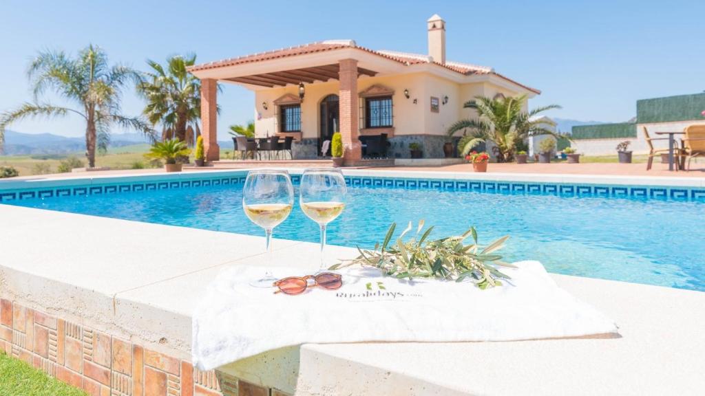 zwei Gläser Wein auf einem Tisch neben einem Pool in der Unterkunft Casa La Era Coin by Ruralidays in Coín