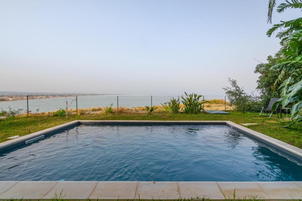 - une piscine avec l'océan en arrière-plan dans l'établissement Eremo degli Oleandri with pool, à Augusta