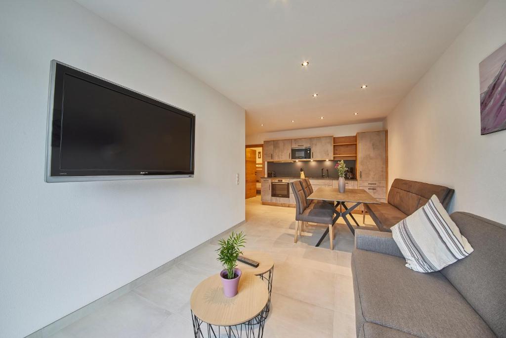 a living room with a couch and a television on a wall at Appartement Atzingerberg in Maishofen