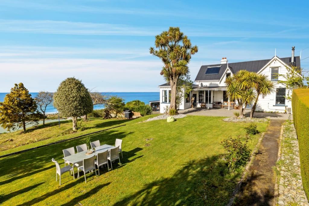 a house with a table and chairs on a lawn at The Professor's Beach House - Brighton Home in Mosgiel