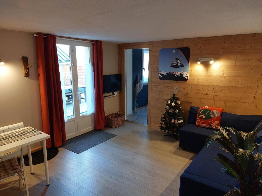 een woonkamer met een bank en een kerstboom bij Studio au pied des montagnes in Le Bourg-dʼOisans