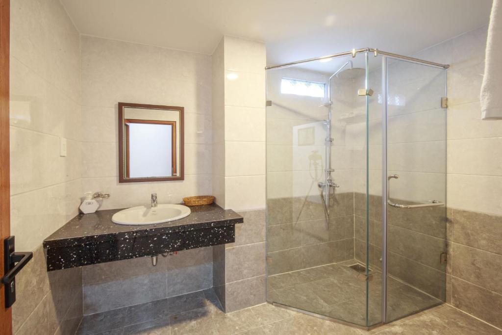 a bathroom with a sink and a glass shower at Ha Nhung Hotel Nha Trang in Nha Trang