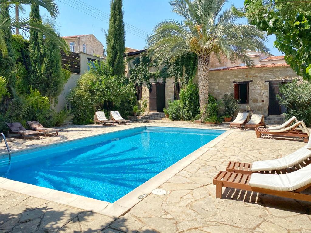 a swimming pool with chaise lounge chairs and a house at Porfyrios Country House in Chirokitia