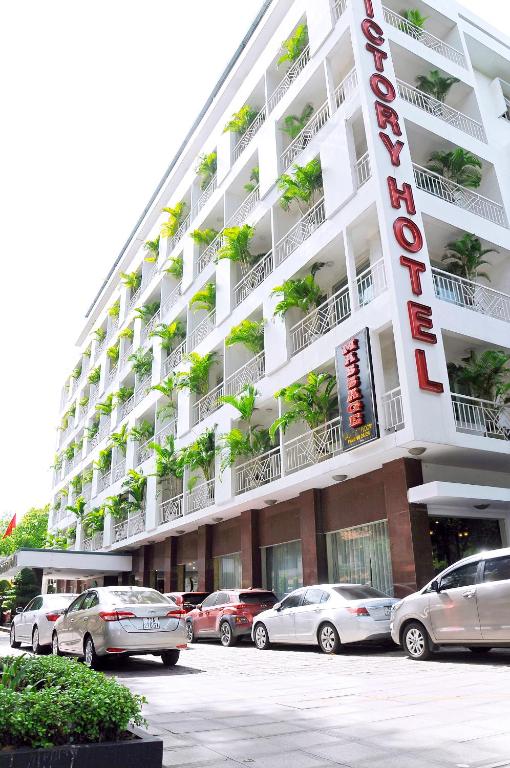 a large hotel with cars parked in front of it at Victory Sai Gon Hotel in Ho Chi Minh City
