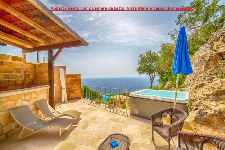 un patio con bañera de hidromasaje, sillas y sombrilla en Villetta Orchidea, en Gagliano del Capo