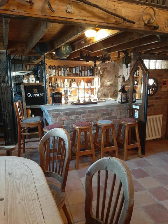 a bar with wooden chairs and a table and a counter at Nellie's Farmhouse in Carlingford