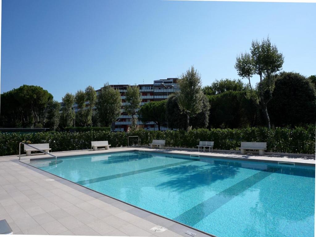 una piscina con bancos y un edificio de fondo en Amazing studio with pool and terrace, en Porto Santa Margherita