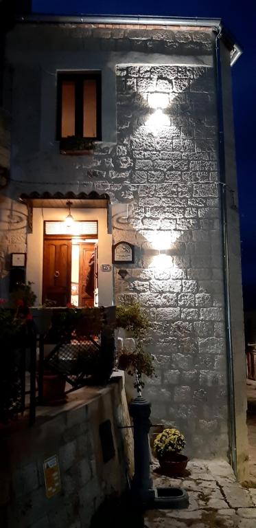 un edificio de piedra con luces en el lateral. en La Casa del Pittore di Petralia, en Petralia Soprana