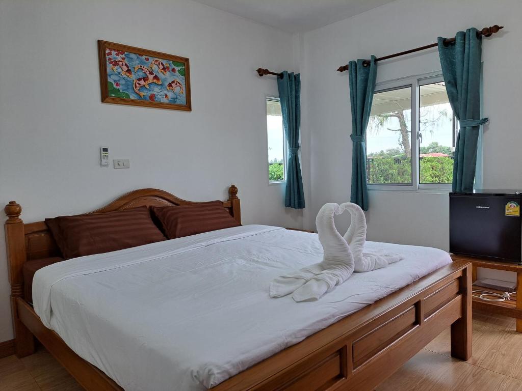 um quarto com uma cama com lençóis brancos e uma televisão em เรือนจำปา ( Rueanjumpa resort ) em Ban Na Kai