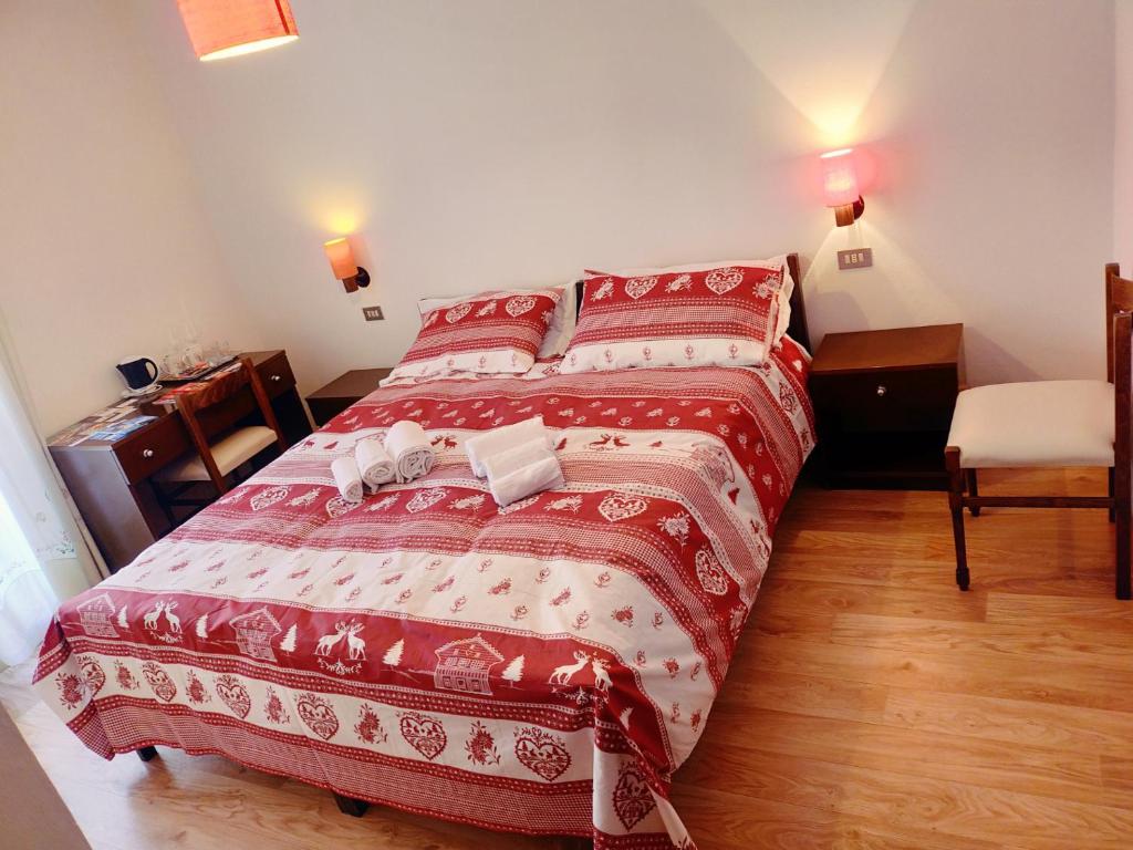 a bedroom with a large bed with red and white sheets at Cèsa Cherpei - Dog Friendly in Campitello di Fassa