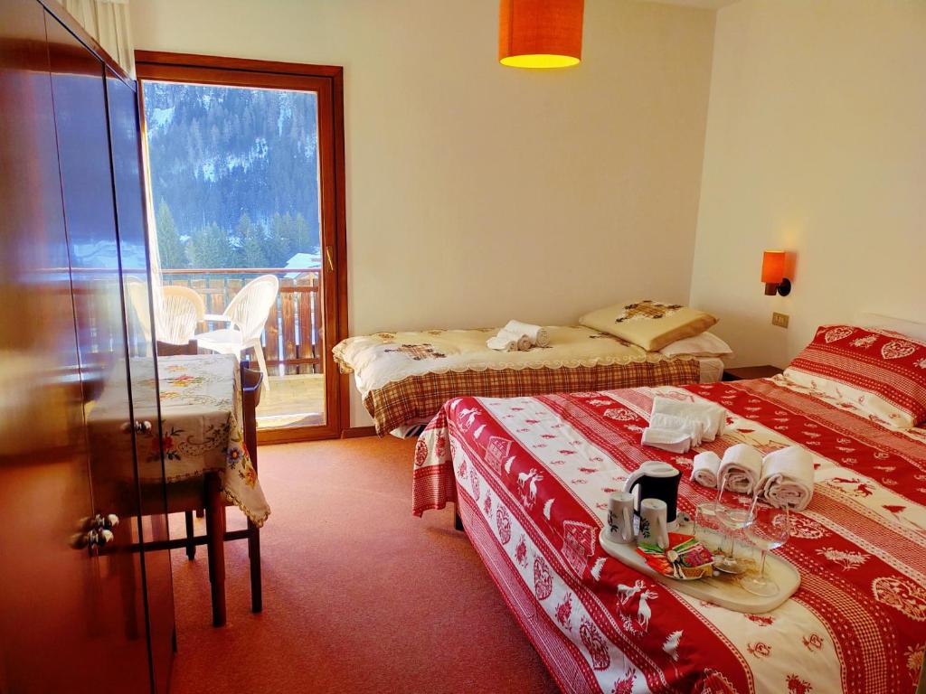 a hotel room with two beds and a balcony at Cèsa Cherpei - Dog Friendly in Campitello di Fassa