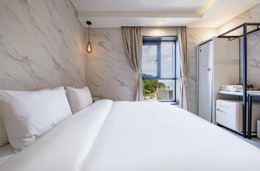 a bedroom with a large white bed and a window at H moment Hotel songjeong in Busan