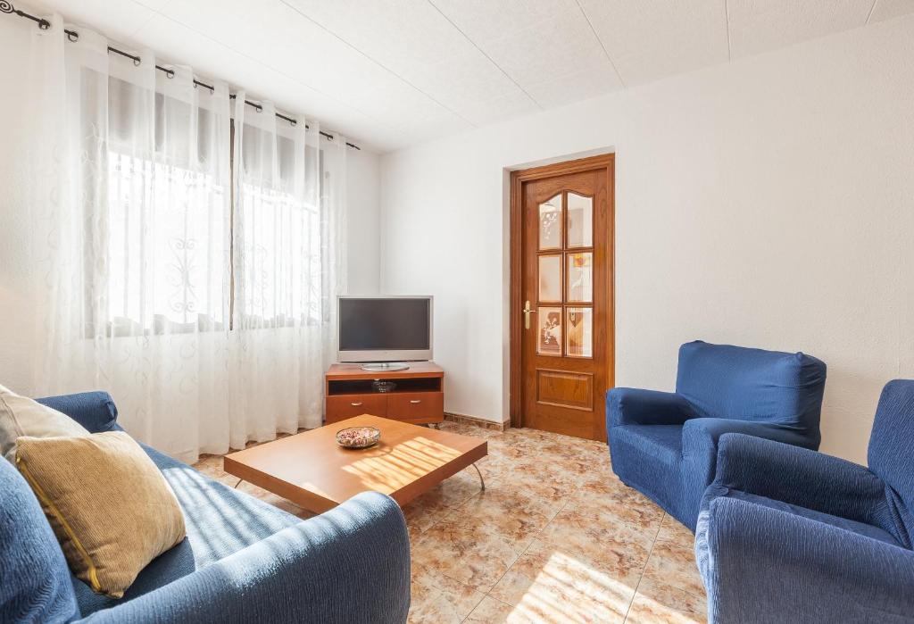 - un salon avec 2 chaises bleues et une télévision dans l'établissement Villa Julia, à Rubí