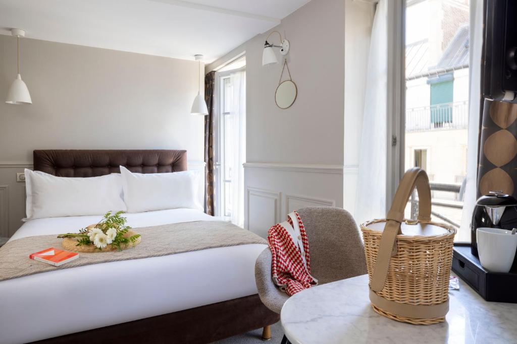 a bedroom with a king sized bed and a table at Hôtel Madeleine Haussmann in Paris