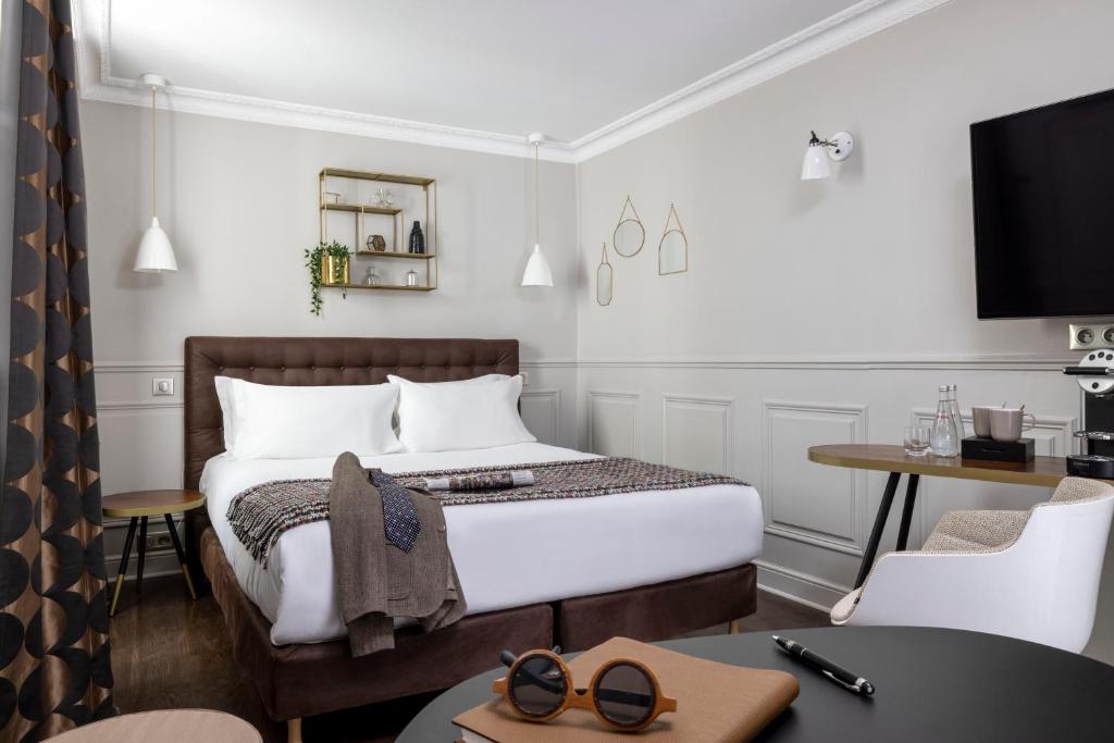 パリにあるホテル マドレーヌ オスマンのベッド、テーブル、椅子が備わるホテルルームです。