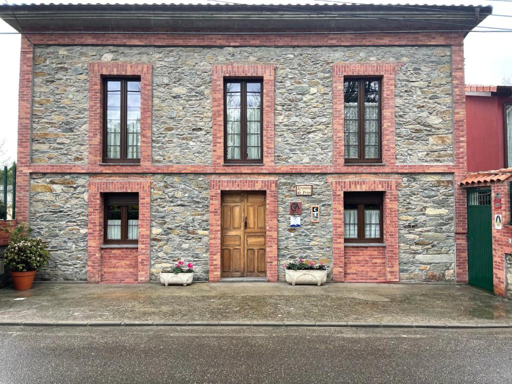 um edifício de tijolos com uma porta de madeira e janelas em La Ermita De Prin em Villademar