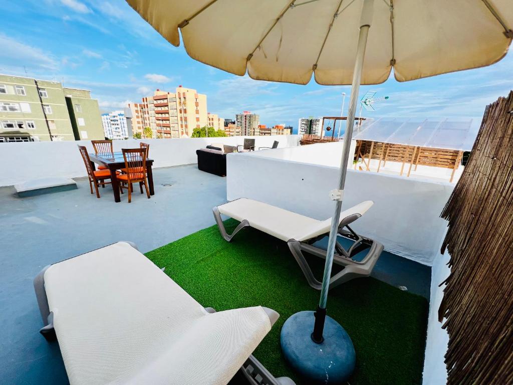 een patio met stoelen en een parasol op een dak bij El jardin de Iris in Santa Cruz de Tenerife