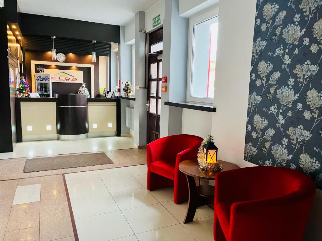 un restaurante con sillas rojas, una mesa y una barra en Hotel Elda en Bydgoszcz