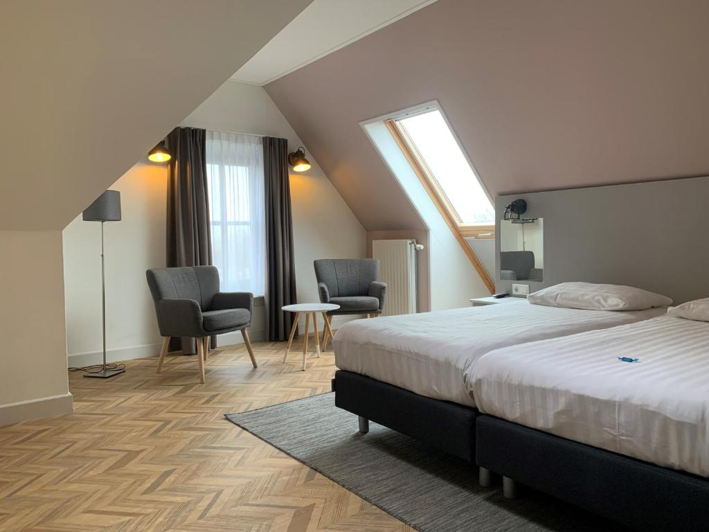 a bedroom with a bed and two chairs and a window at Hotel In den Brouwery in Domburg