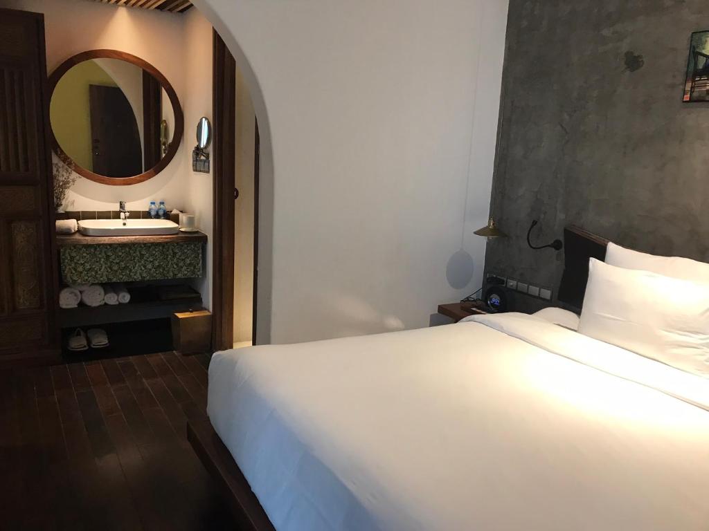 1 dormitorio con cama blanca y espejo en Nancy Grand Strip Villa Imperial 1, en Vung Tau