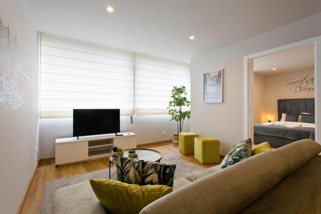 uma sala de estar com um sofá, uma televisão e uma cama em APOSENTUS - Marta's House em Porto