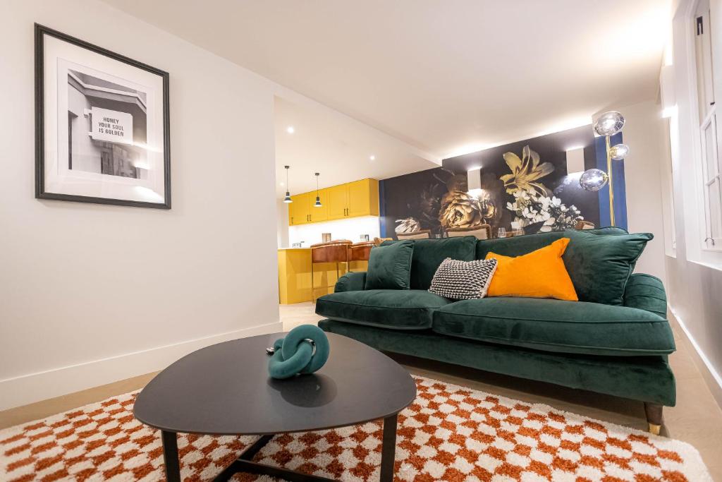 a living room with a green couch and a table at Three Bedroom Apartments near Spitalfields Market and Tube Station in London