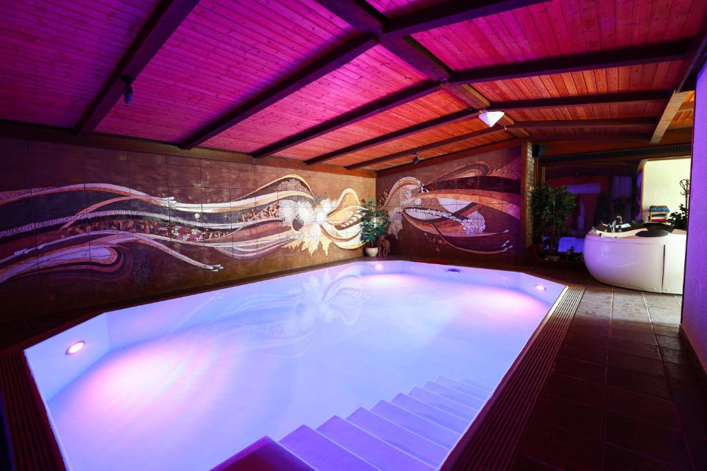 a swimming pool in a bathroom with a painting on the wall at Ferienhaus mit Schwimmbad, Whirlpool & Sauna am Nürburgring in Leimbach