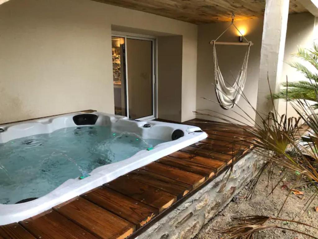 une baignoire jacuzzi sur une terrasse dans une maison dans l'établissement Les Palmiers. Charme, spa et massage en vignoble nantais, au Pallet