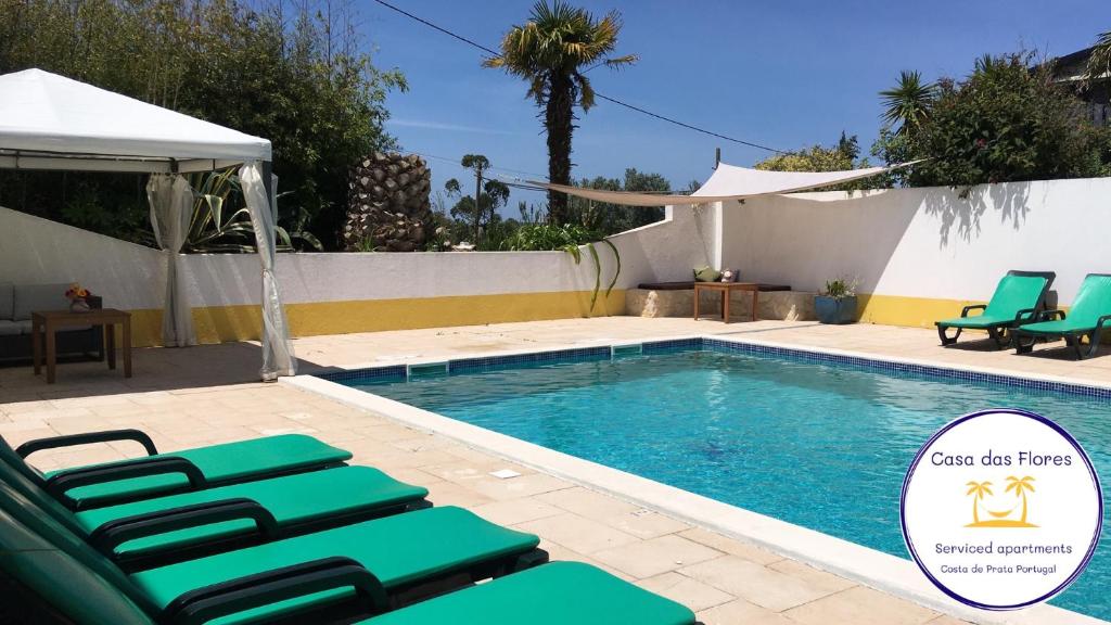 a swimming pool with green lounge chairs next to it at Casa das Flores in Monte Redondo