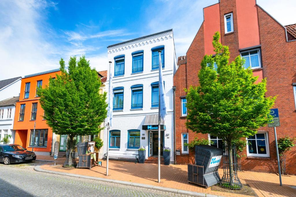 un bâtiment situé dans une rue bordée d'arbres et de bâtiments dans l'établissement Nordsee-Hotel Hinrichsen, à Husum