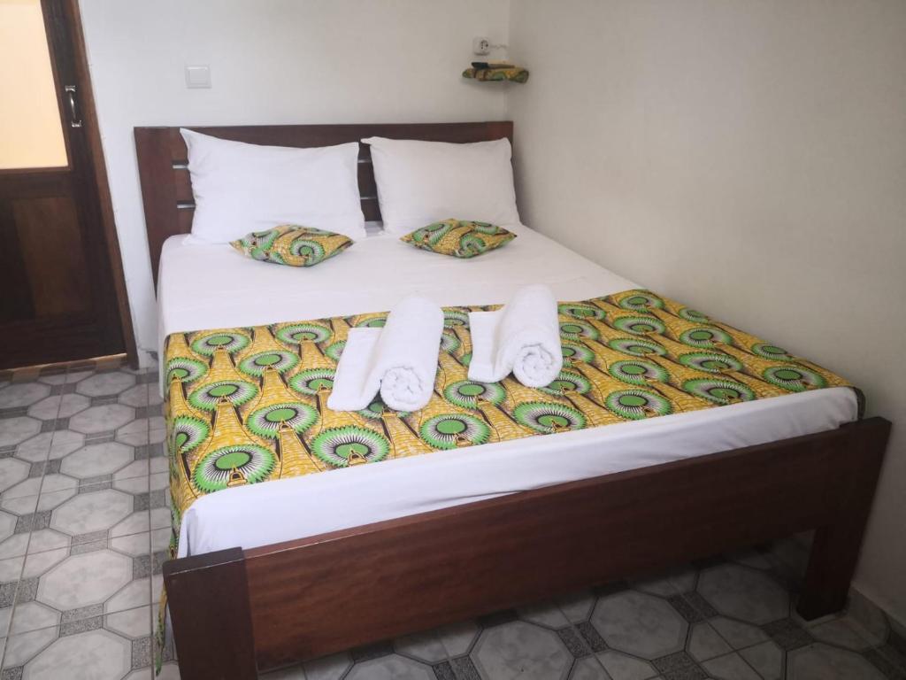 a bed with two towels and two pillows on it at Micaval Residential in São Tomé