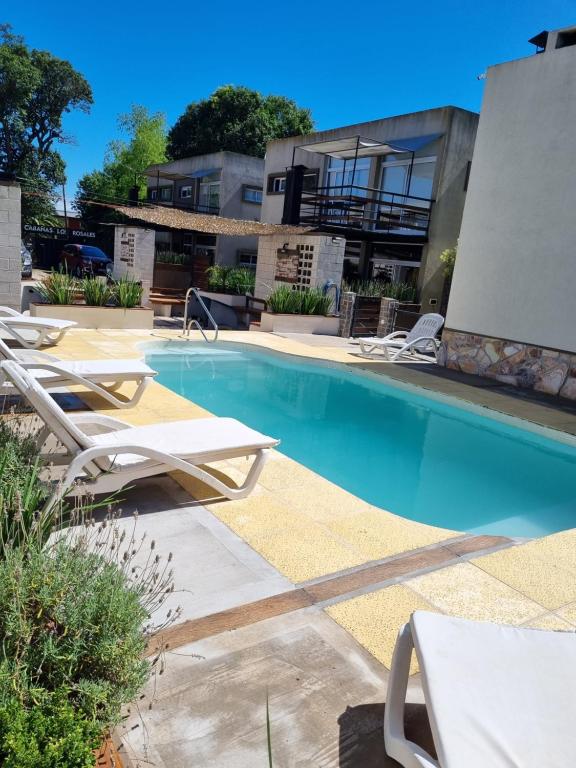 une piscine avec des chaises longues et un bâtiment dans l'établissement Laguna Park Duplex & Suites, à Chascomús