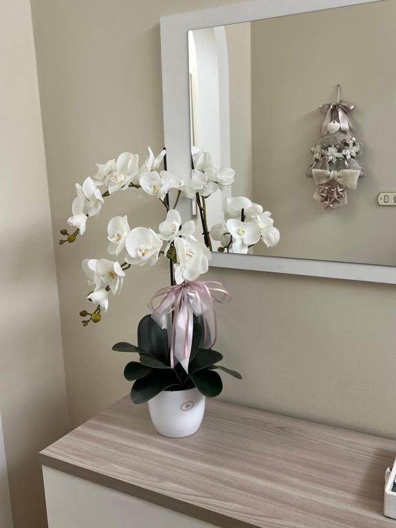 een witte vaas met witte bloemen op een tafel bij Casa vacanze l’orchidea in Soci