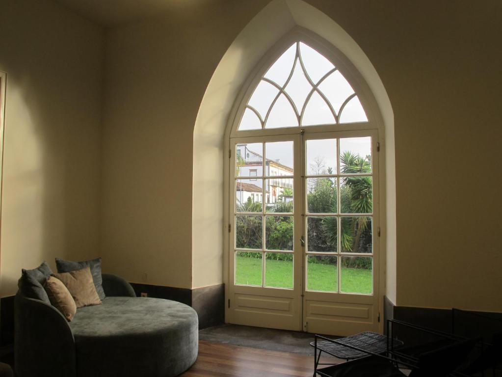 una puerta arqueada en una habitación con silla y ventana en Azores Youth Hostels - Sao Miguel, en Ponta Delgada