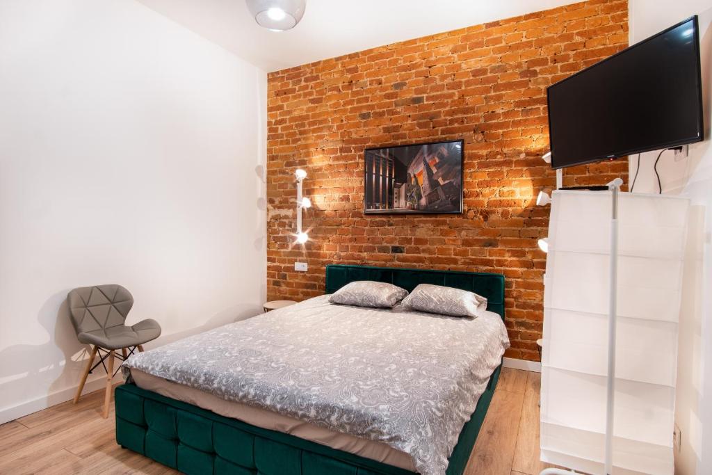 a bedroom with a bed and a brick wall at Dream Aparts - Studio przy Piotrkowskiej in Łódź