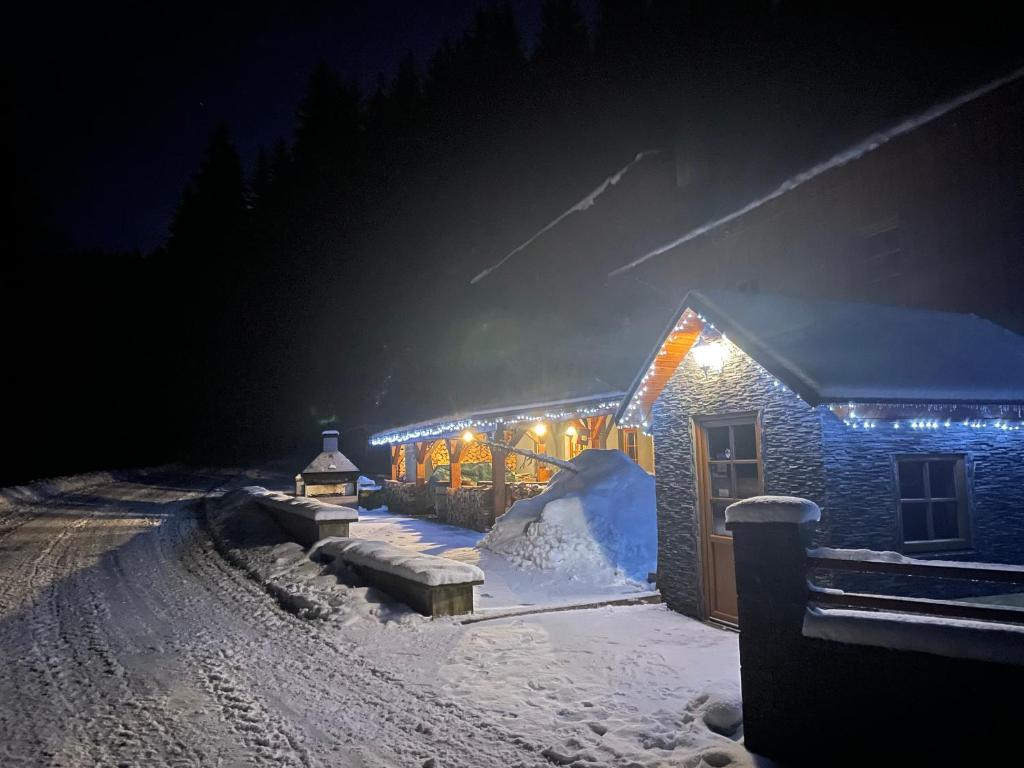 una casa coperta di neve di notte con luci di Kamenný Mlýn a Strážné